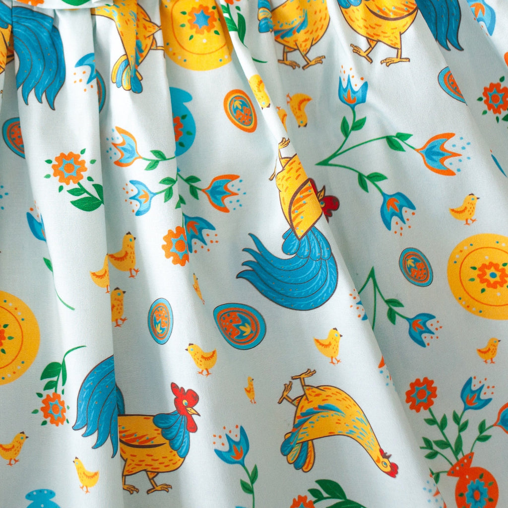 Girls' cotton dress Xenia with traditional Eastern European rooster and chick design, symbolizing prosperity and cultural heritage.
Dívčí bavlněné šaty Ksenia s tradičními východoevropskými motivy kohouta a kuřátek, symbolizujícími prosperitu a kulturní dědictví.